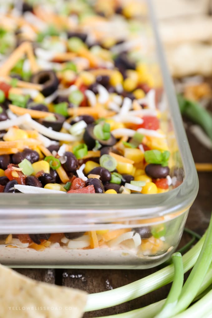 Southwestern Seven Layer Dip - Layers of kicked up tomatoes, black beans and corn on top of a spicy, cream cheese base. This is the appetizer you'll want to bring to every party! southwestern 7 layer dip view from the side