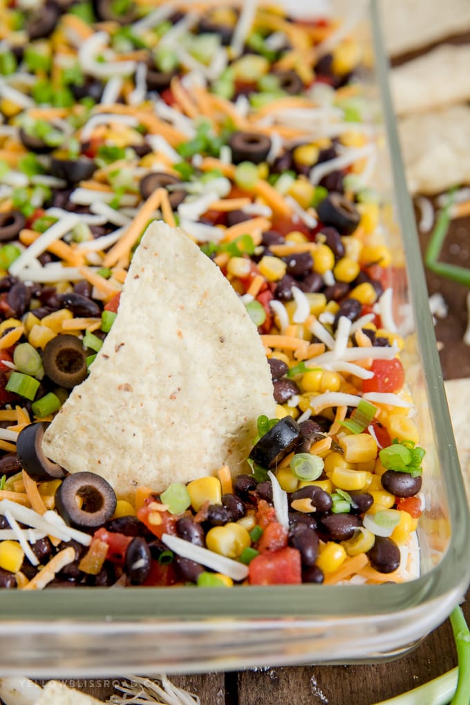 southwest 7 layer dip with a tortilla chip stuck in it