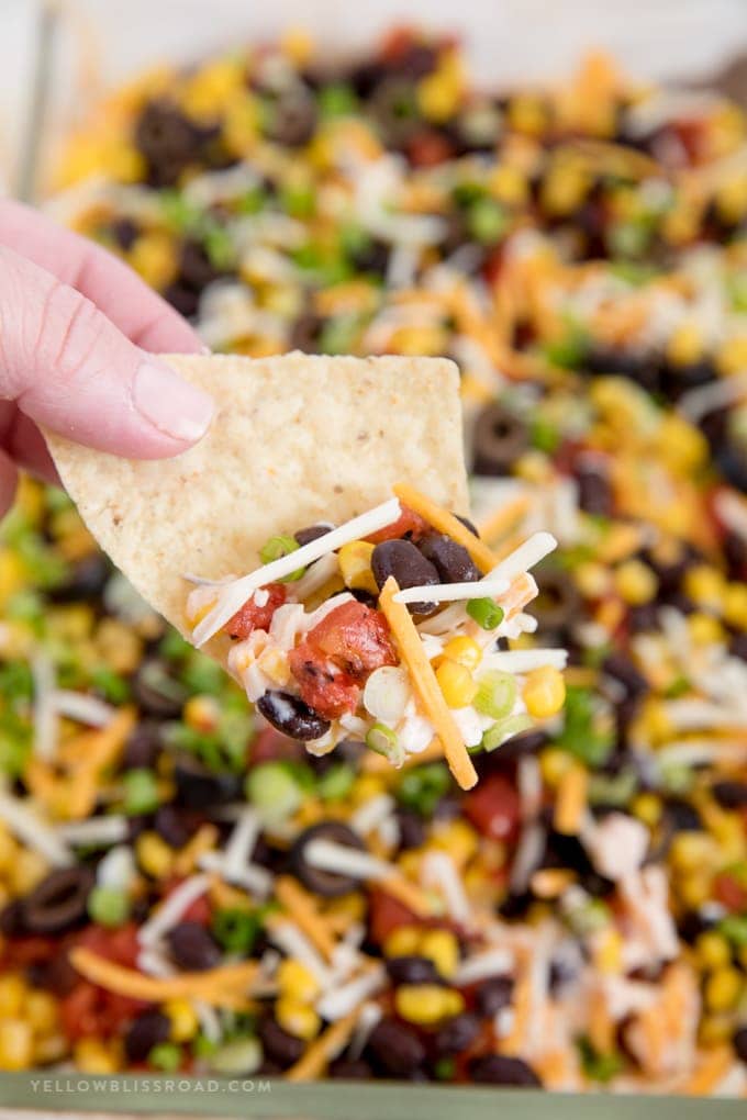 southwest 7 layer dip on top of a tortilla chip