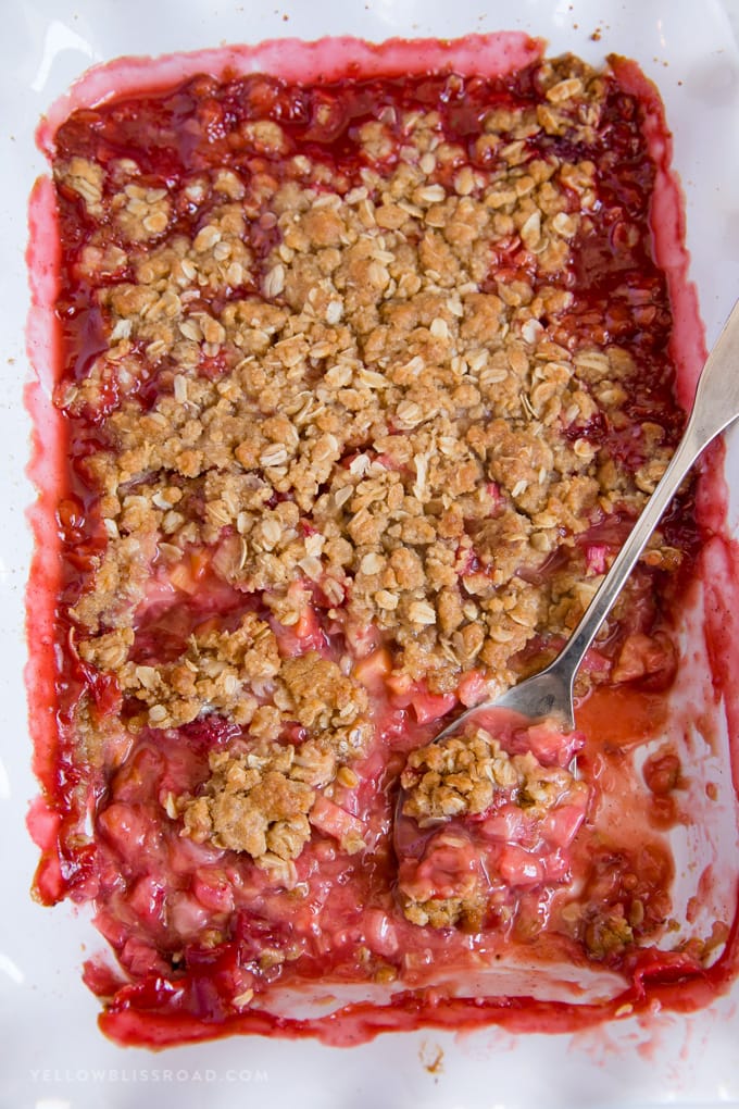 Strawberry Rhubarb Crisp in a white baking dish with a spoon