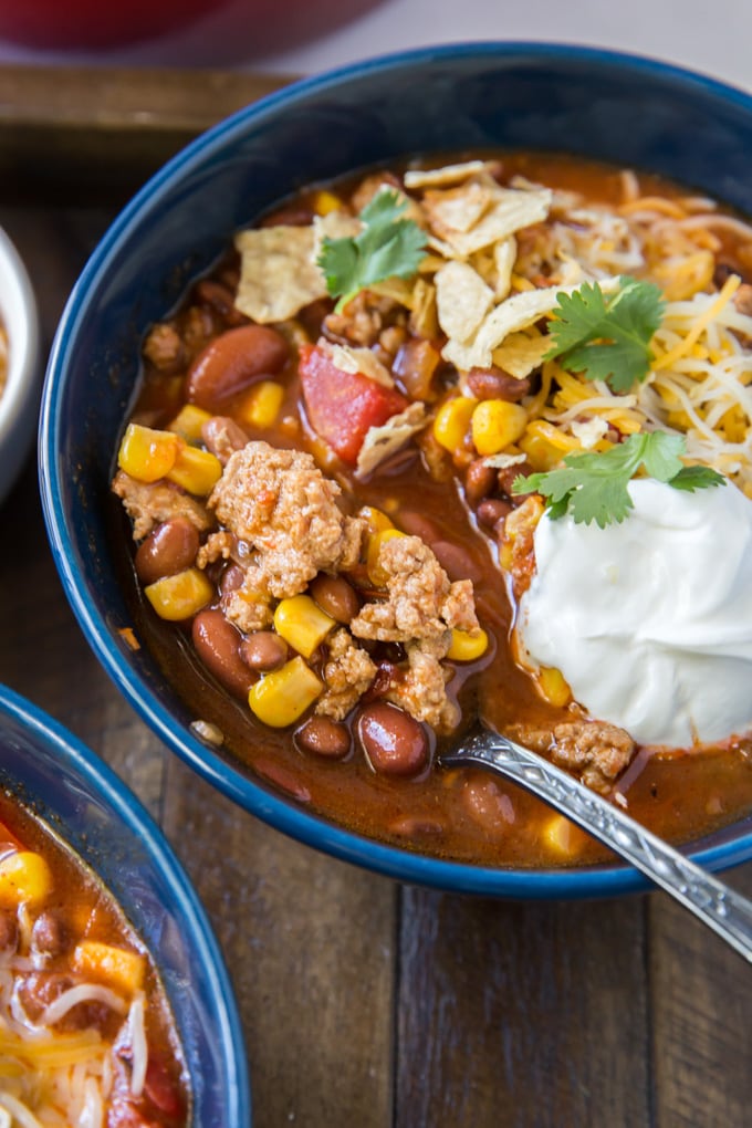 a bowl of taco soup with a spoon lifted out of the bowl showing the ground turkey 