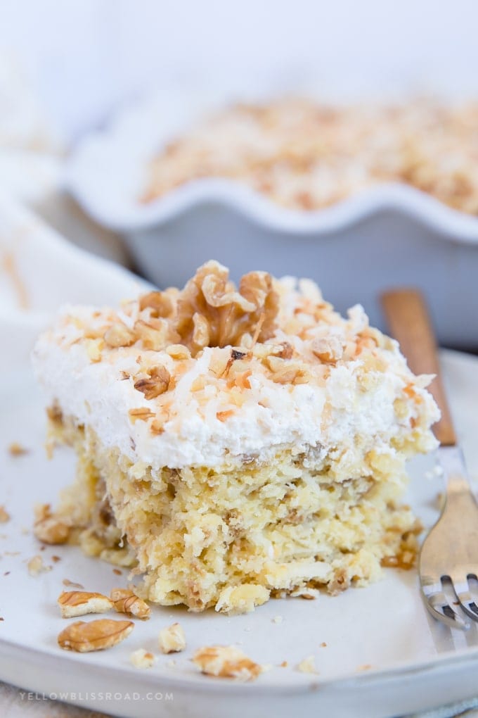 slice of walnut pineapple cake with coconut on a plate with a fork