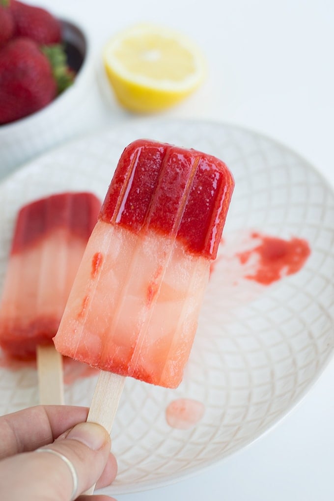 Hand holding a strawberry lemonade popsicle