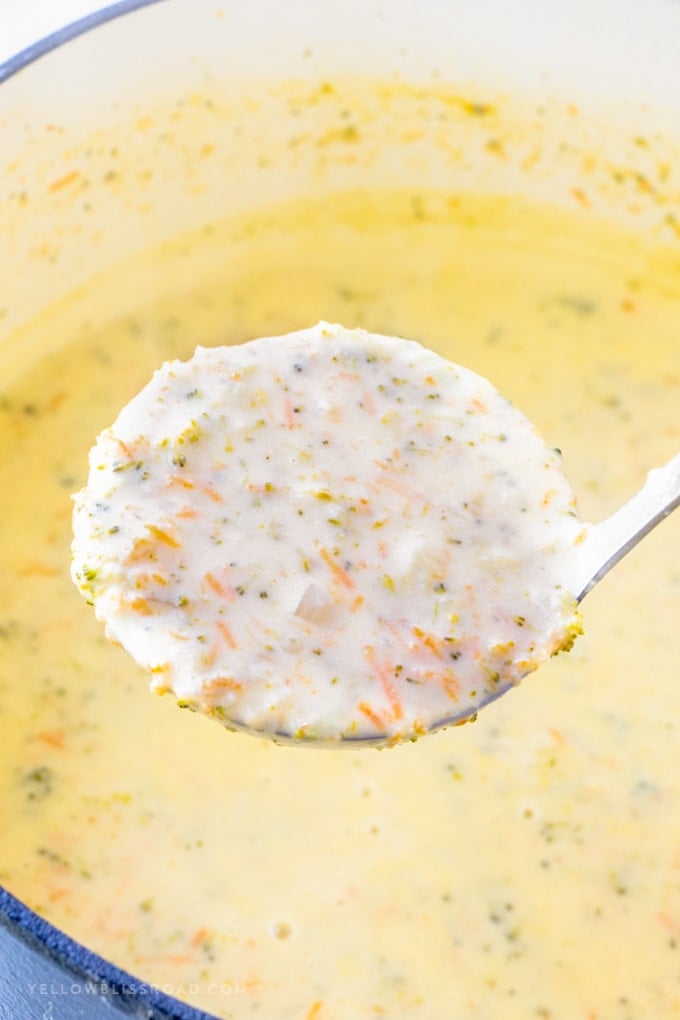 A ladle of broccoli cheese soup over a pot of the soup.