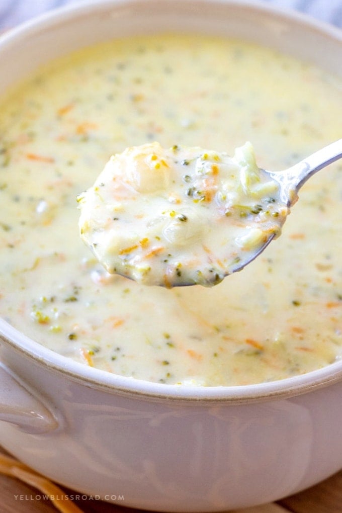 A bowl full of broccoli cheese soup with a spoonful pulled out.