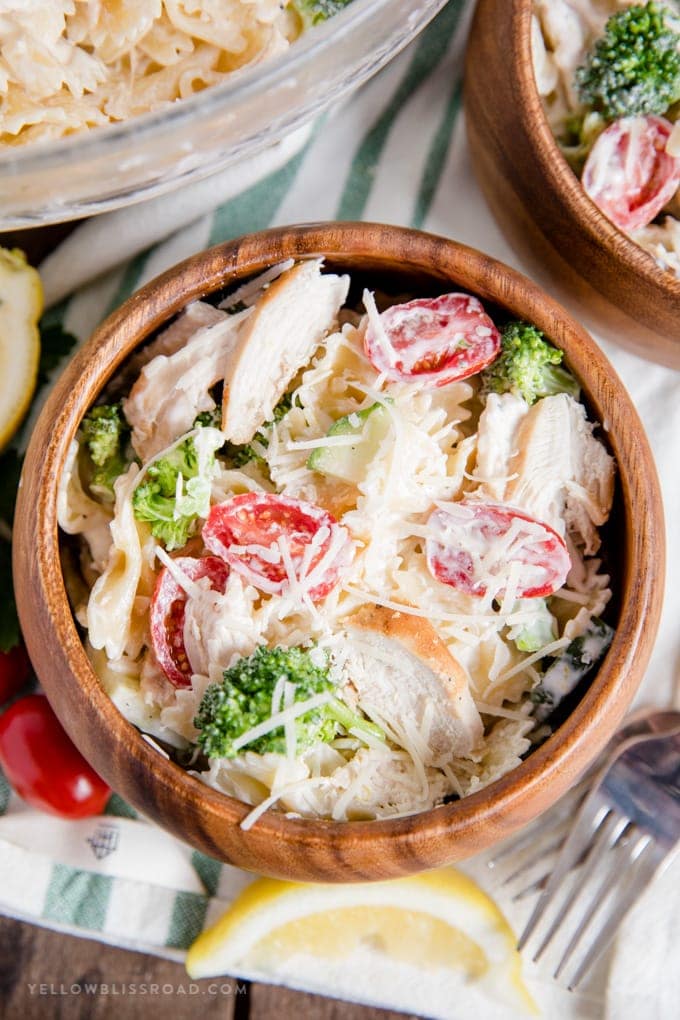 wood bowl with chicken, pasta, vegetables, fork, lemon slice