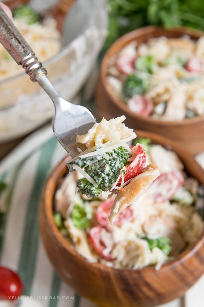 chicken pasta salad in wooden bowls, chicken, brocoli, toamto on a fork