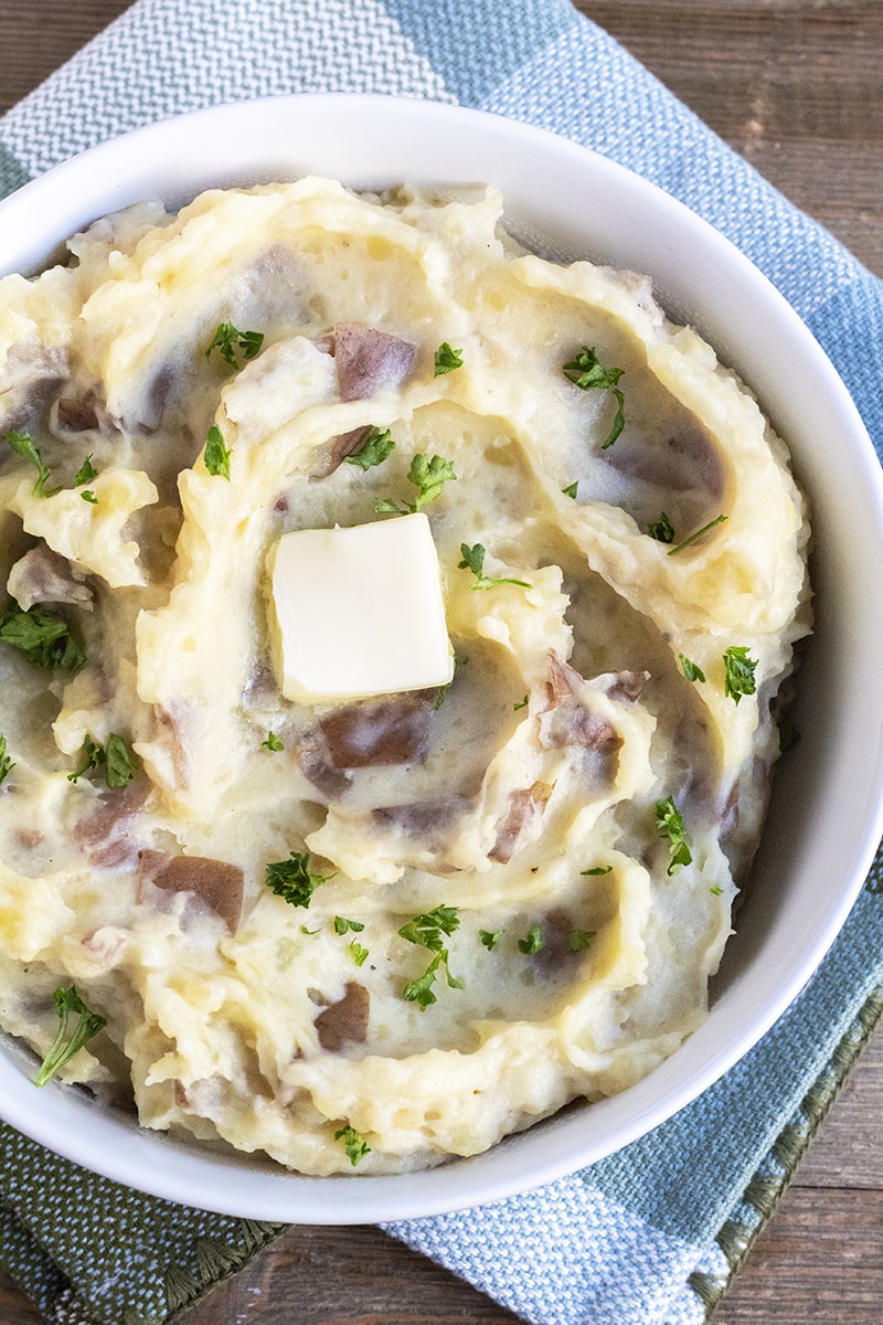These Garlic Mashed Potatoes are creamy and delicious. Made with minced garlic and cream cheese, it's the best side dish and one that everyone will love! over head picture of garlic mashed potatoes in a serving bowl