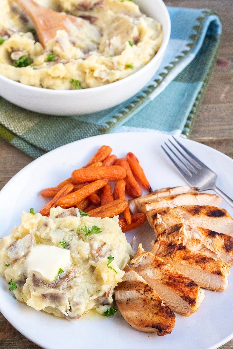 Want more easy potato recipes? Easy Instant Pot Mashed Potatoes World's Best Mashed Potatoes Loaded Mashed Potatoes Cheesy Scalloped Potatoes Baked Cheesy Ranch Potatoes Easy Cheese and Ranch Potatoes garlic mashed potatoes on a dinner plate with honey roasted carrots and grilled chicken