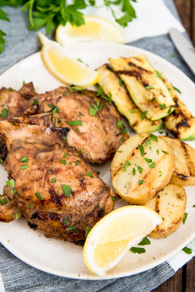 A great grilled chicken marinade is essential for summer grilling. This delicious marinade packs a flavor punch and is perfect for all kinds of chicken! Grilled Chicken Marinade recipe - chicken on a plate with grilled potatoes and zucchini and lemon