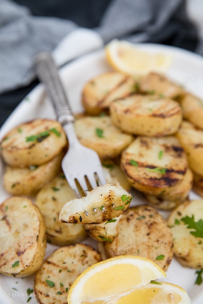 These Grilled potatoes are so simple and easy - they will become your new favorite summer side dish! a piece of a grilled potato on a fork
