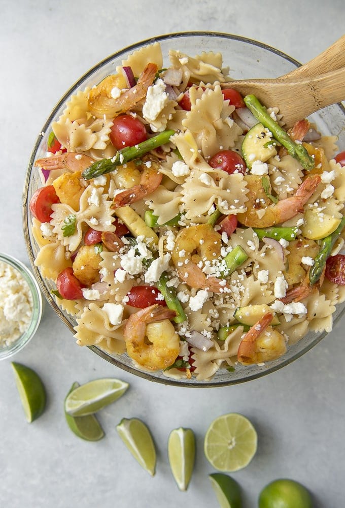 overhead shot of Grilled Shrimp Pasta Salad in a serving bowl with serving spoons