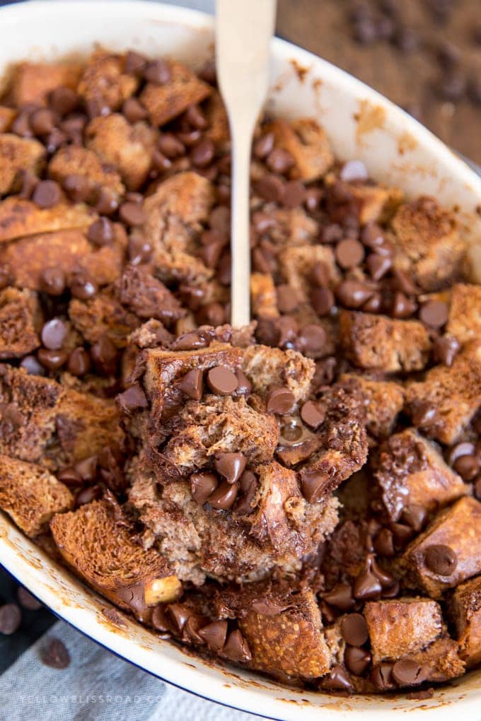 chocolate bread pudding in a baking dish with a spoonful of a serving on top.