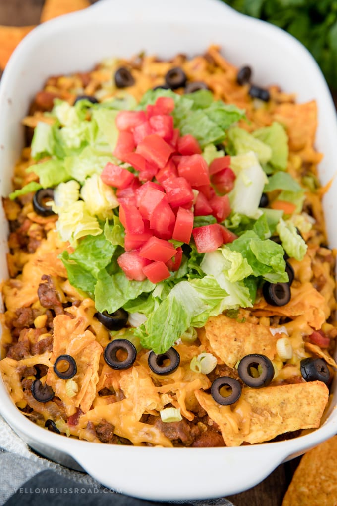 Dorito Taco Salad Casserole topped with shredded lettuce and tomatoes and olives