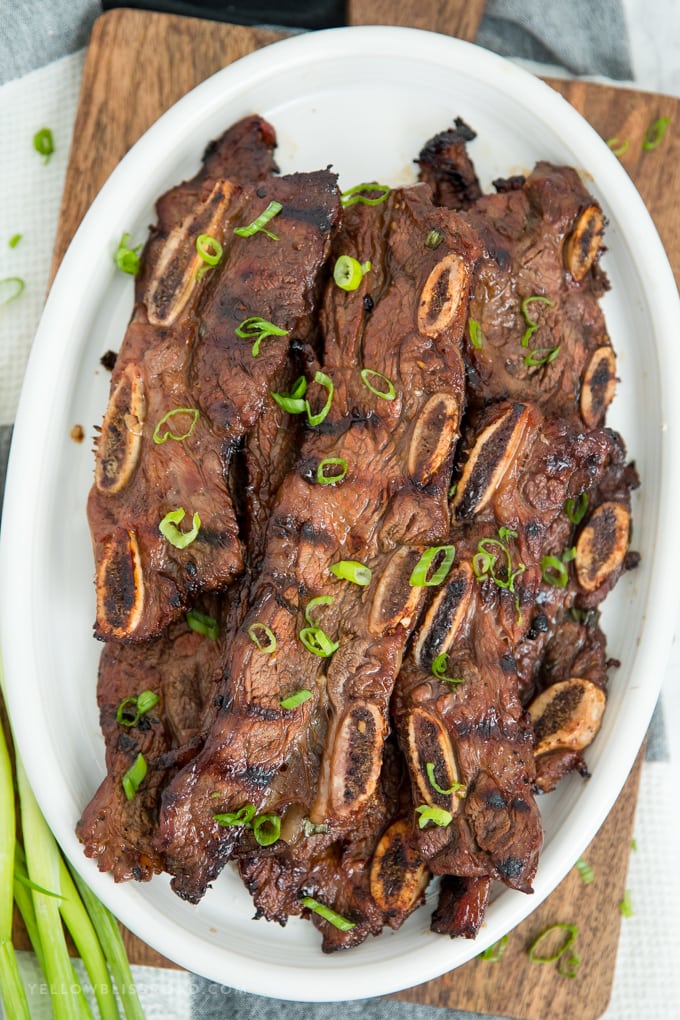Grilled Korean Short Ribs are so tender and full of flavor! Marinated in a tangy Kalbi style marinade for hours, this juicy short rib recipe is a sure hit! A plate of Korean Short Ribs, grilled to perfection