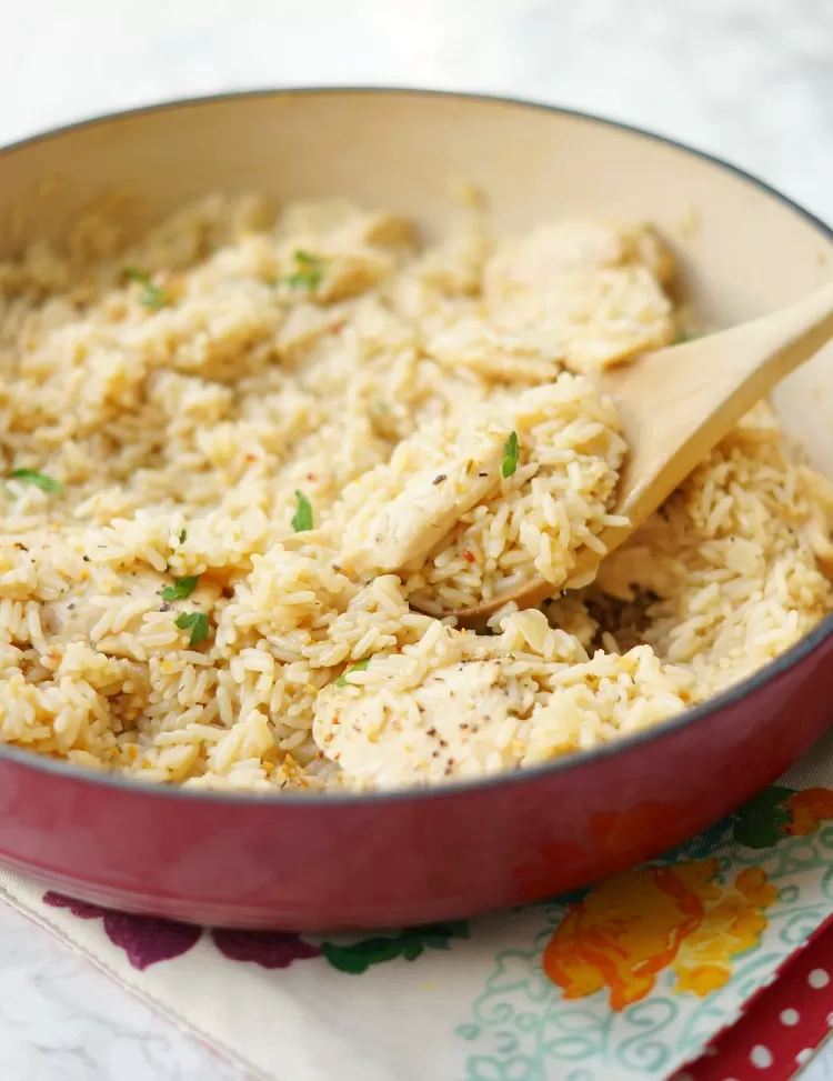 a portion of Skillet Garlic Chicken and Rice Casserole being spooned out of skillet