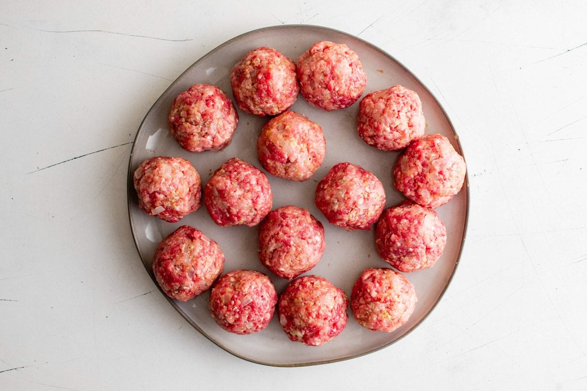 Raw meatballs on a round tray.