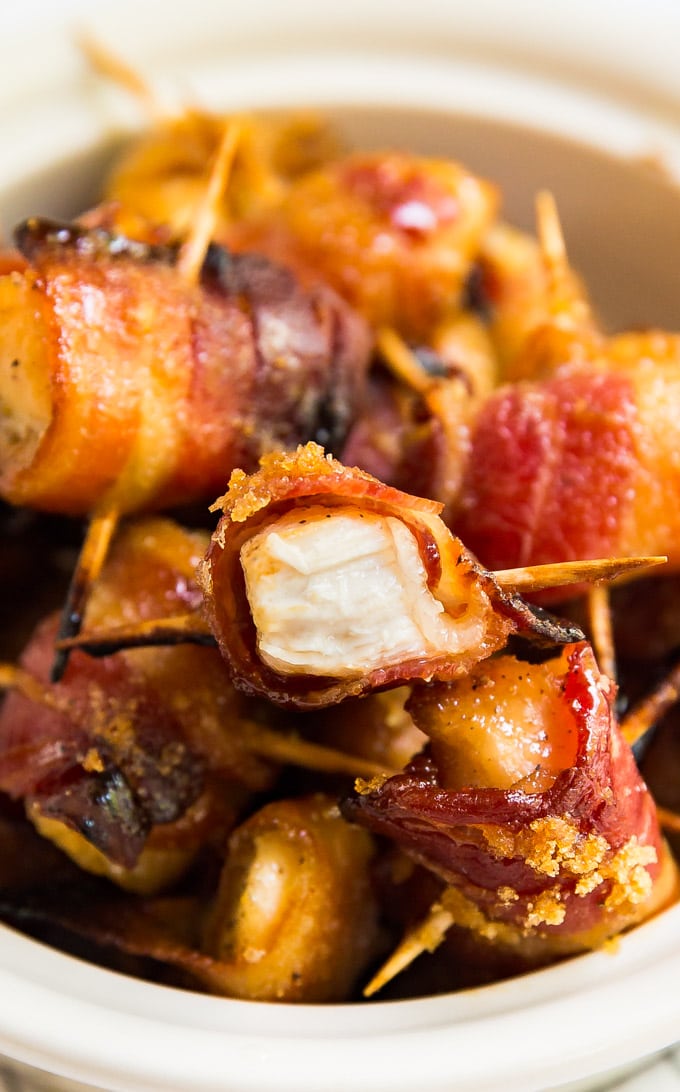 a bowl of Bacon Wrapped Chicken Bites with one cut in half to show the inside