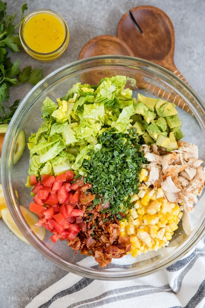 Ingredients to make Bacon Avocado Chicken Salad with Lemon Vinaigrette in a clear glass bowl