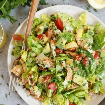 A bowl of salad, with Chicken, bacon and tomatoes and avocado