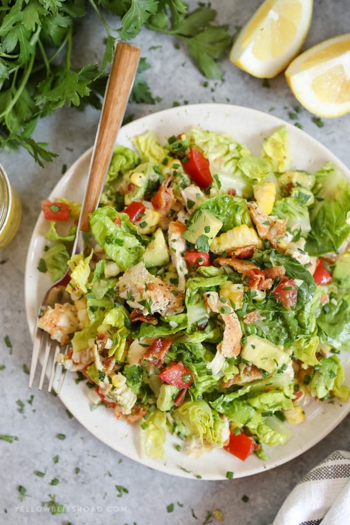 A bowl of salad, with Chicken, bacon and tomatoes and avocado
