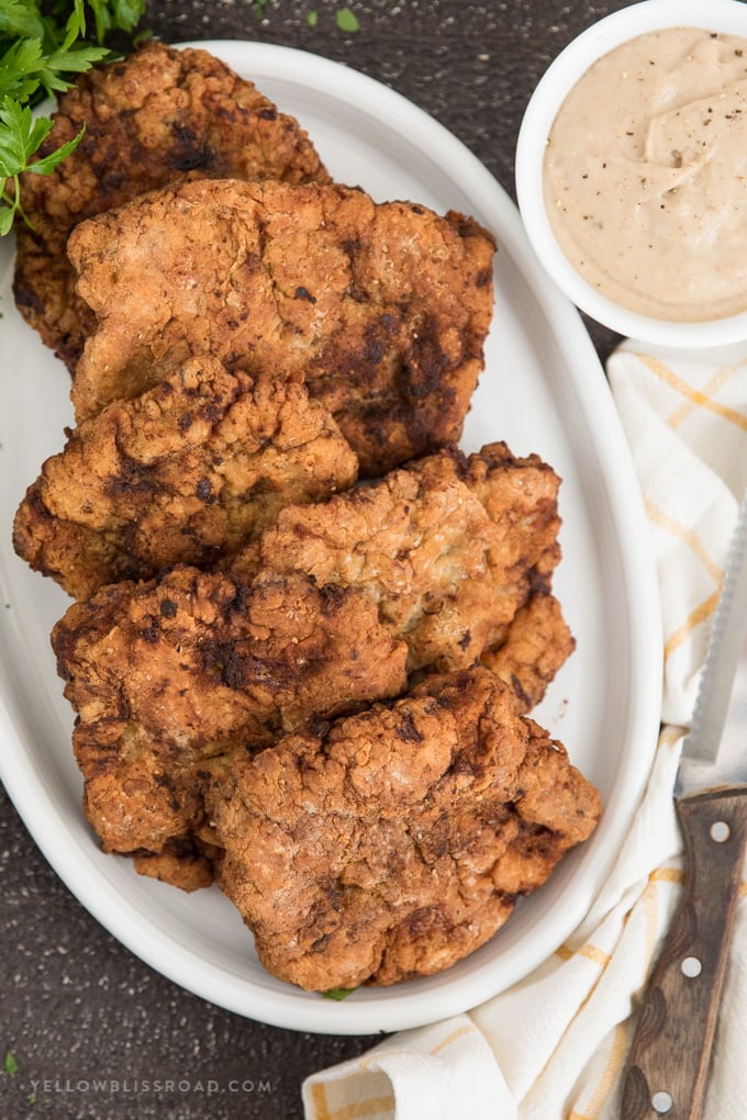 This Chicken Fried Steak Recipe is made with lightly breaded and fried cube steak and a creamy homemade gravy. Perfect for breakfast or dinner. chicken fried steaks with a side of homemade gravy.