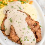A plate of chicken fried steak with gravy on top
