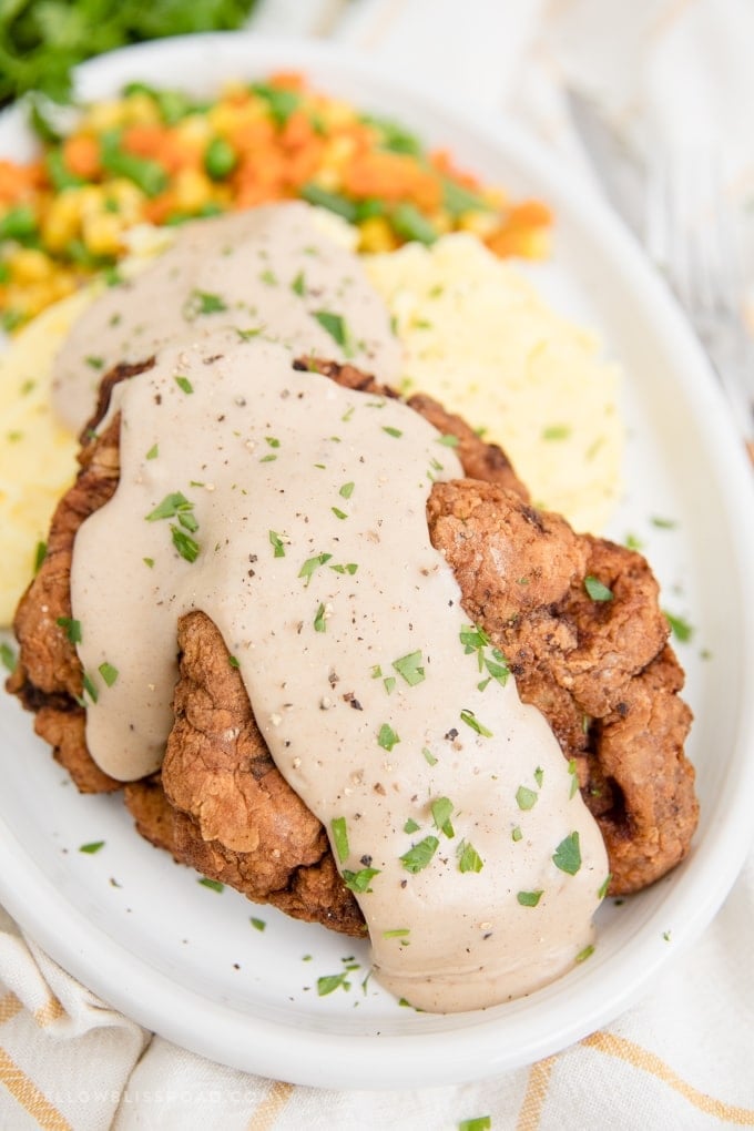 chicken fried steak with gravy, mashed potatoes and vegetables