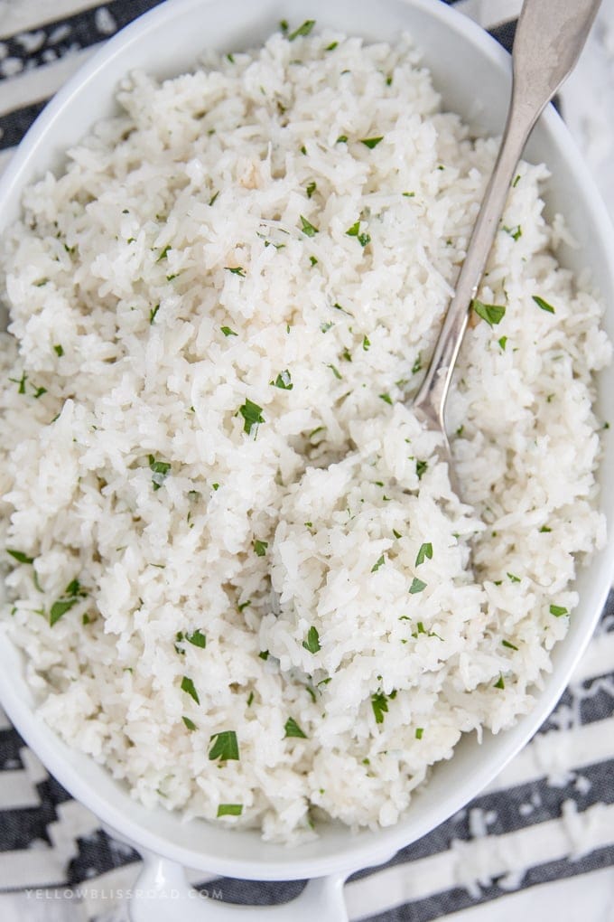 Coconut rice in a white baking dish with a silver spoon.