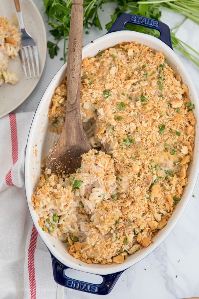 My Tuna Casserole Recipe is pure, classic comfort food for a weeknight dinner. Tuna, noodles and peas in a cheesy homemade sauce with a crunchy cracker crumb topping. A large pan of tuna noodle casserole with a wooden spoon