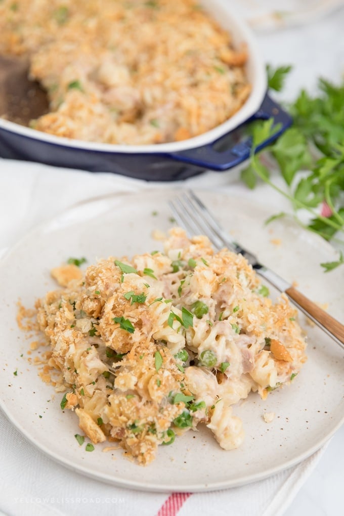 My Tuna Casserole Recipe is pure, classic comfort food for a weeknight dinner. Tuna, noodles and peas in a cheesy homemade sauce with a crunchy cracker crumb topping. Tuna casserole recipe with a generous helping on a plate.