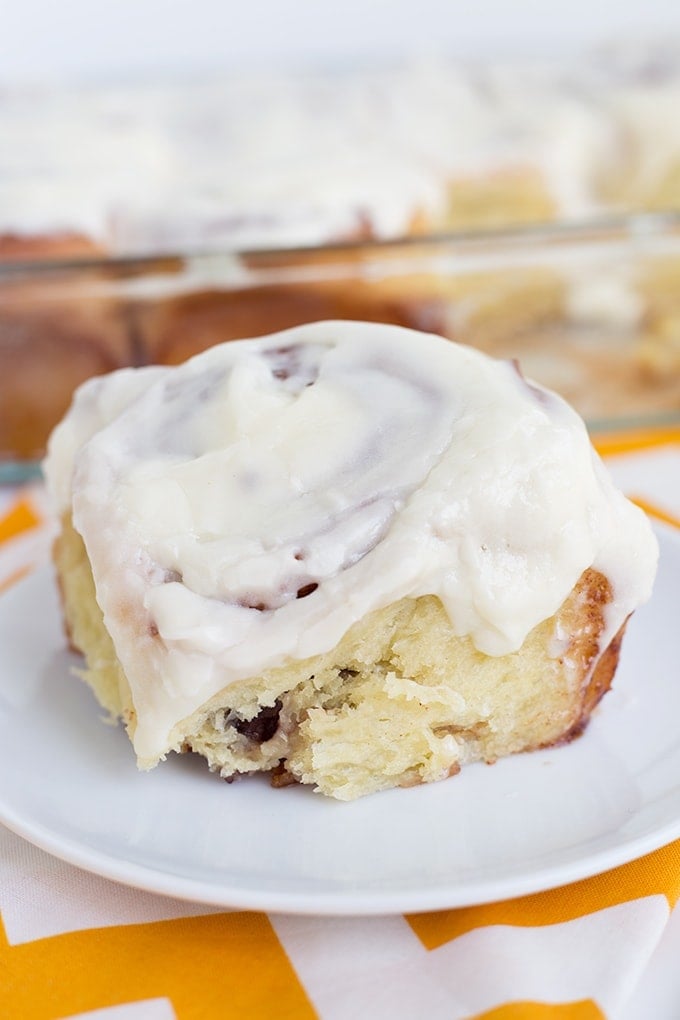 These homemade cinnamon rolls are so soft & gooey and baked to a golden brown perfection before being smothered in cream cheese frosting. I can't imagine breakfast without them! homemade cinnamon roll on a small plate