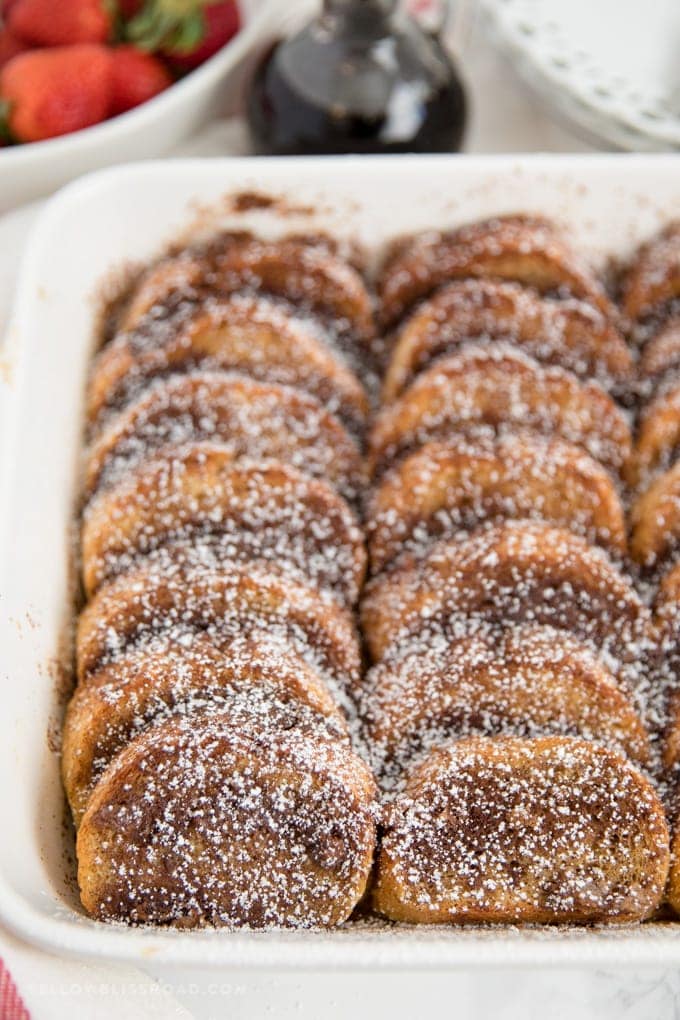 A white baking dish full of slices of baked french toast.