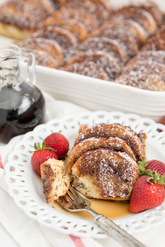 a slice of baked french toast on a plate with syrup and strawberries.