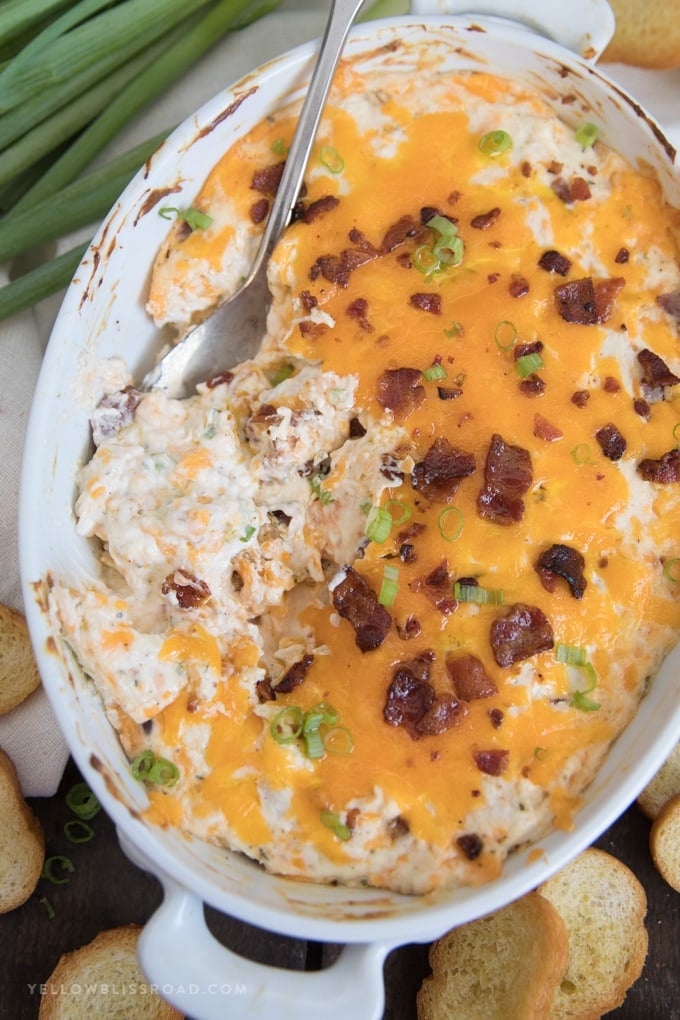 Chicken + Bacon + Ranch + Cheese = a creamy and indulgent Chicken Crack Dip. Highly addictive and the perfect party appetizer. Chicken Crack Dip in a casserole baking dish with a silver spoon.