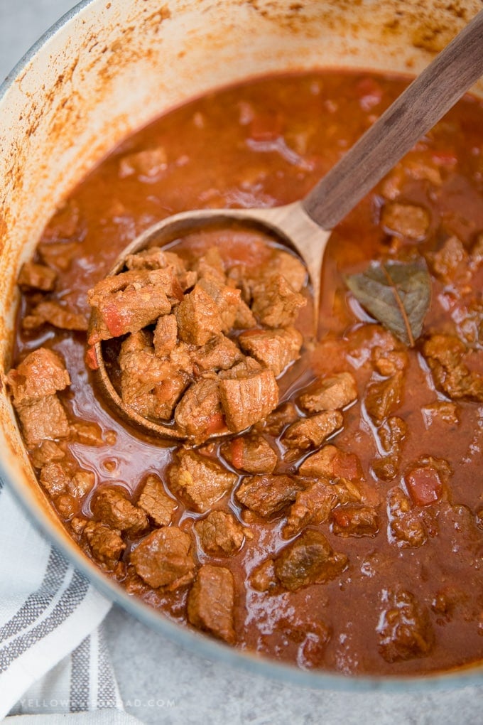 Authentic Hungarian Goulash in a large pot with a wooden ladle.