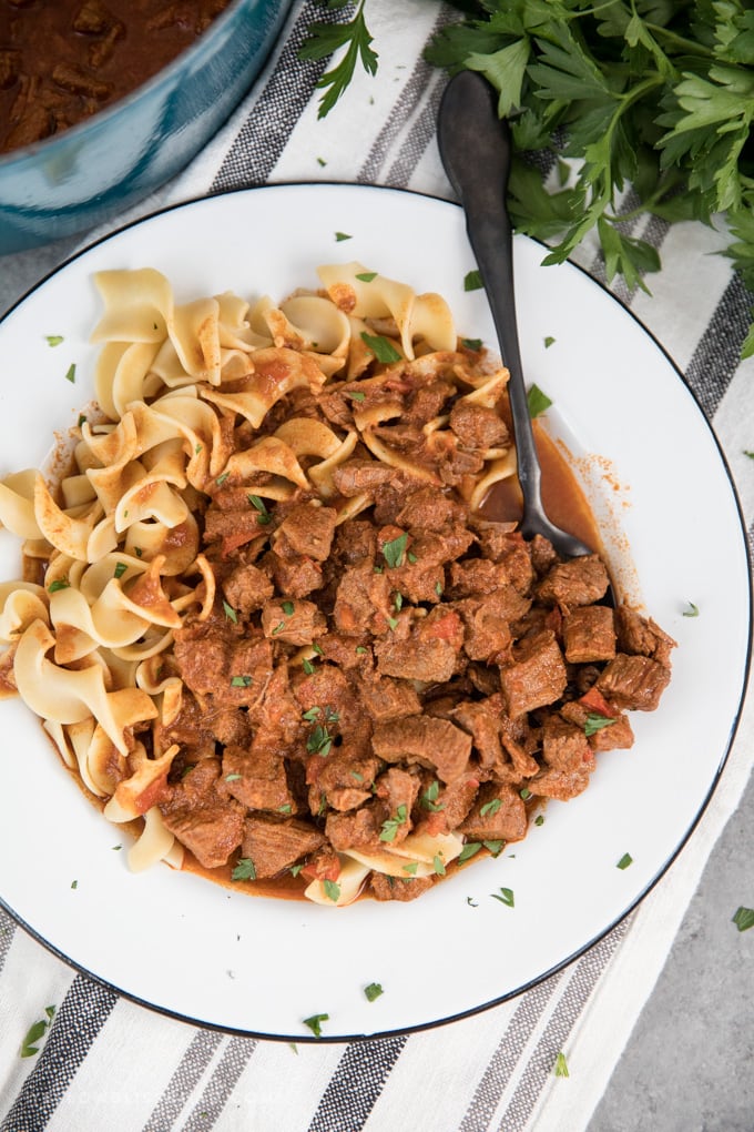 Authentic Hungarian Goulash in a shallow white bowl with a black spoon.