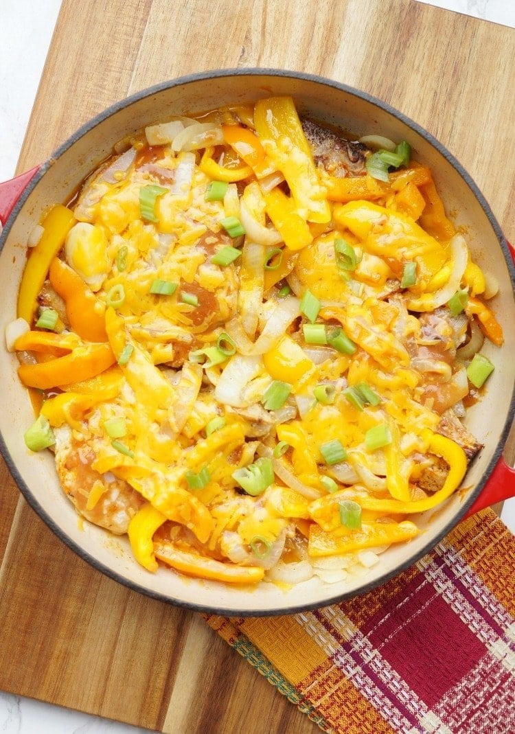 skillet of pork chops smothered in onion, bell pepper, and BBQ ranch sauce