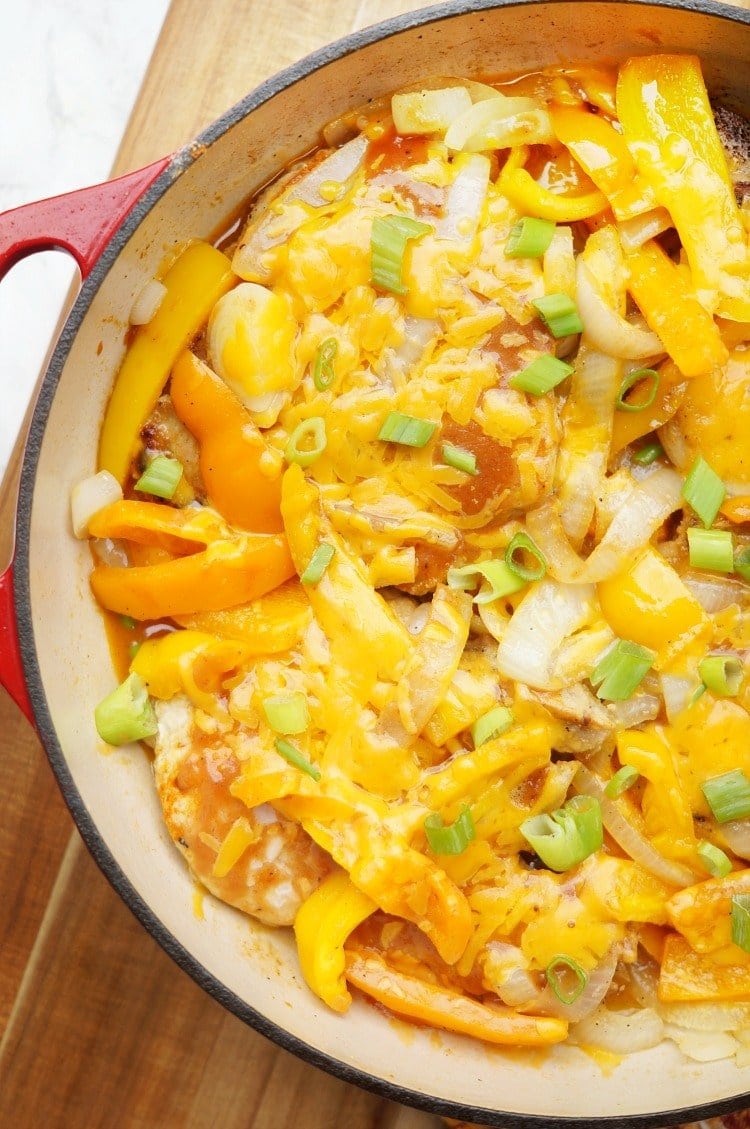 one pot smothered pork chops topped with cheese, onion, bell pepper, and green onion