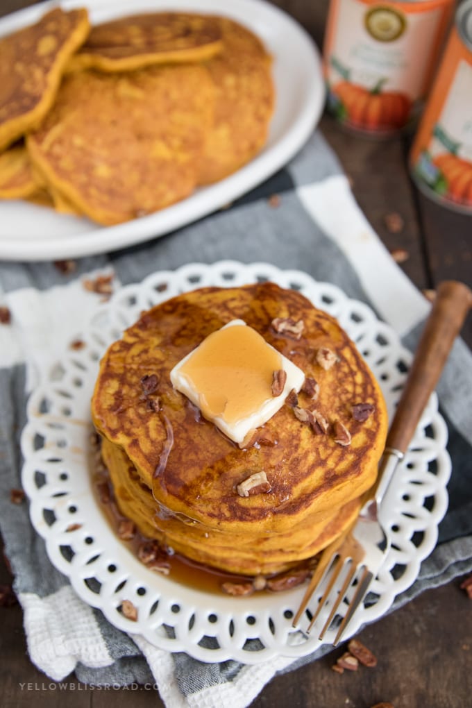 a plate of pumpkin pancakes with syrup and a fork.