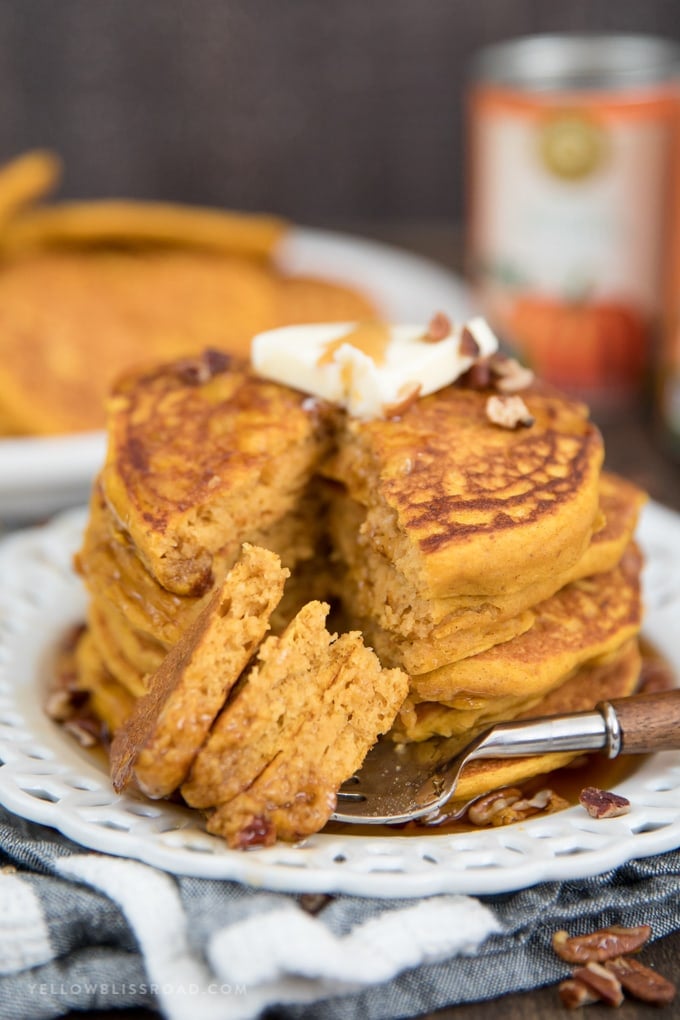 Pumpkin Pancakes are the best way to do celebrate fall! Treat your family this weekend with this delicious breakfast. pumpkin pancakes on a plate with pieces on a fork.