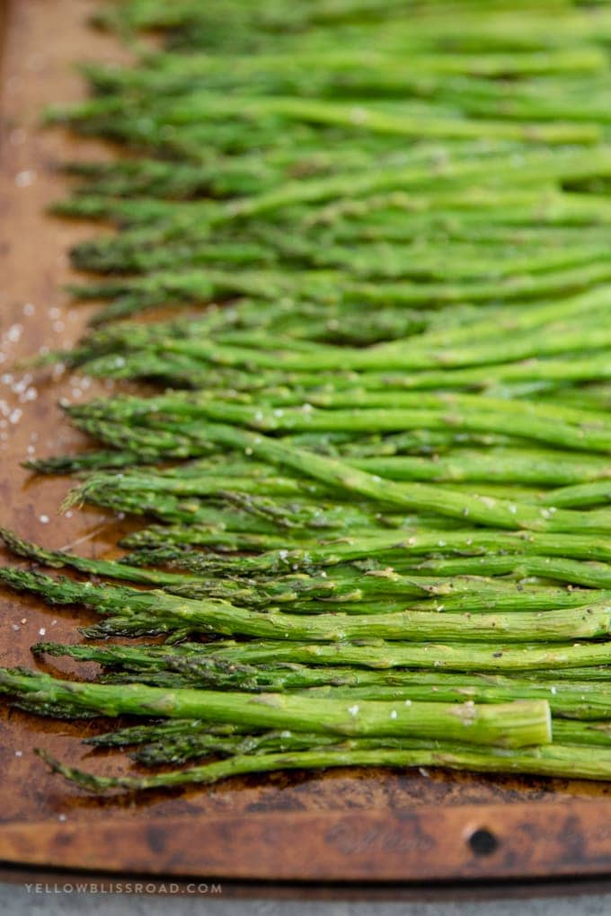 A close up image of roasted asparagus on a baking sheet