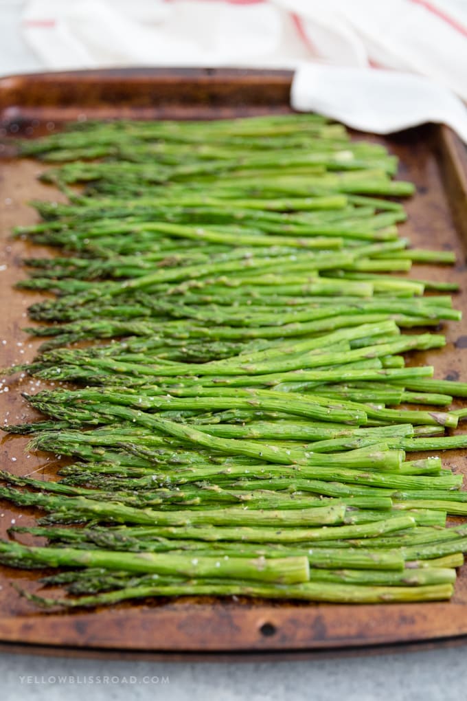Easy Oven Roasted Asparagus is a perfect side dish for any meal. It's simple, requires just a few ingredients, and takes just about 20 minutes to make. Easy oven roasted asparagus on a dark baking sheet.