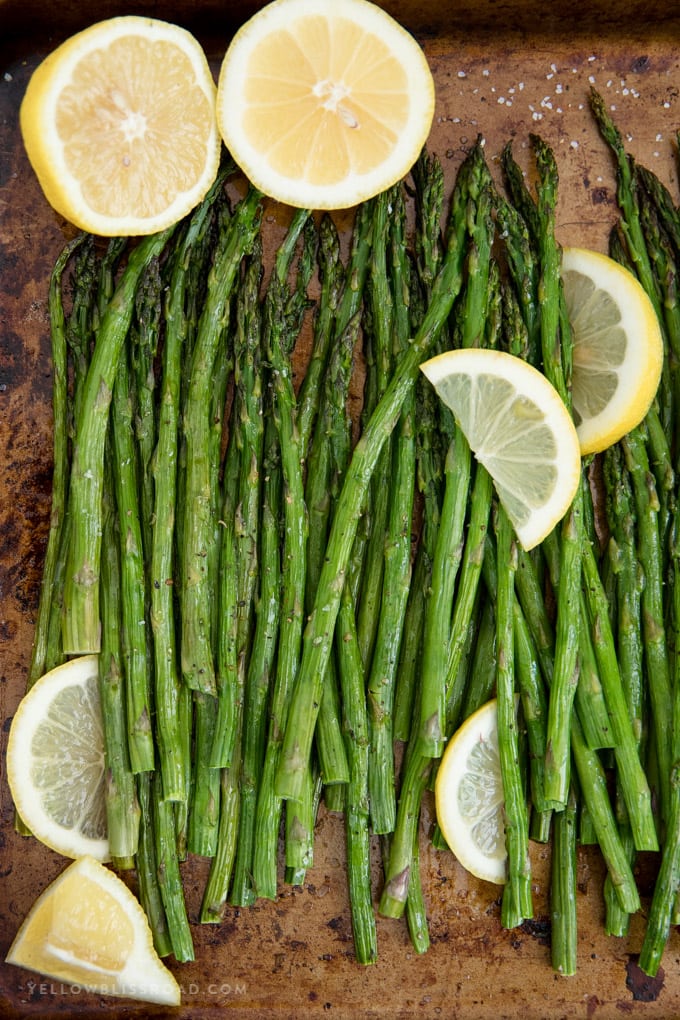 Easy Oven Roasted Asparagus is a perfect side dish for any meal. It's simple, requires just a few ingredients, and takes just about 20 minutes to make. Easy oven roasted asparagus with lemons on a baking sheet.