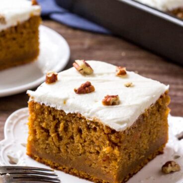 2 slices of sweet potato cake with marshmallow frosting and the pan of cake in the background.