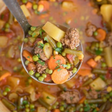 A ladle filled with Beef Vegetable Soup