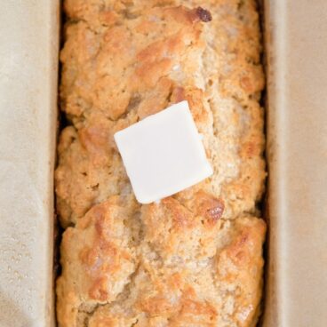 A loaf of homemade bread with butter on top.