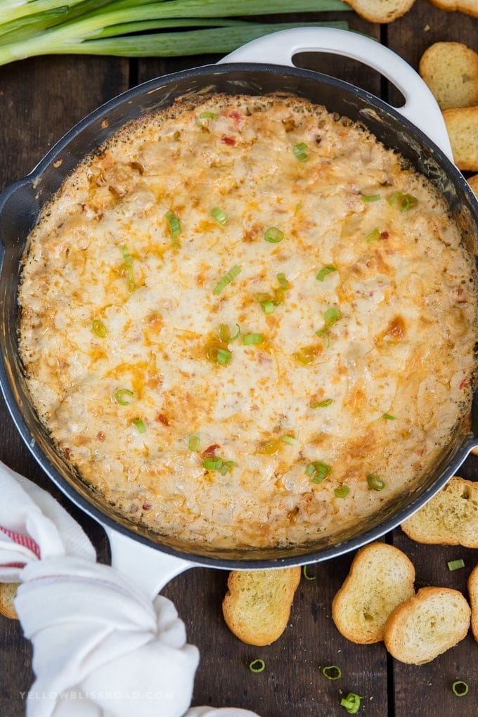 Overhead shot of cream cheese shrimp dip with crostini and green onions.