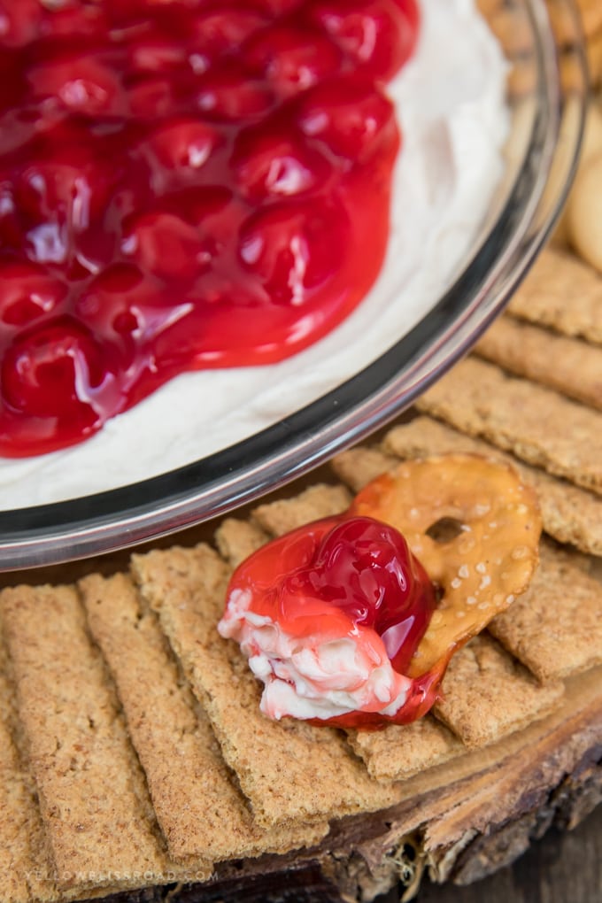No Bake Cherry Cheesecake Dip is a yummy dessert for any occasion. Made with a sweet cream cheese base and cherry pie topping. Cherry Cheesecake Dip on a pretzel with graham cracker and vanilla wafers.
