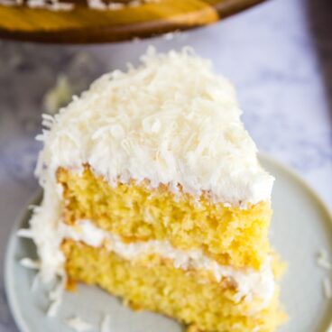 This perfectly moist Coconut Cake will be your new favorite cake for entertaining! No one will ever know it's made by hacking a boxed cake mix!